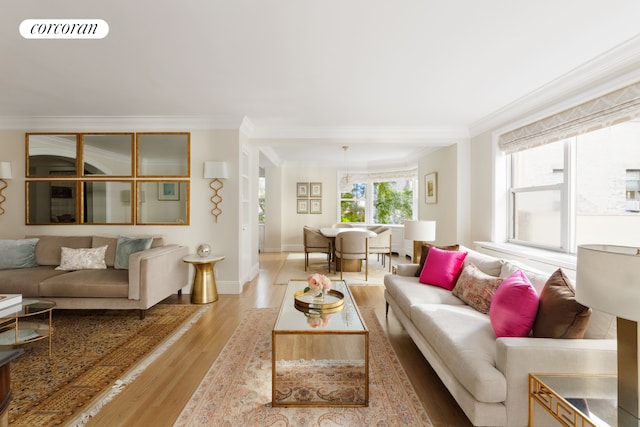 living room featuring ornamental molding, visible vents, light wood-style flooring, and baseboards