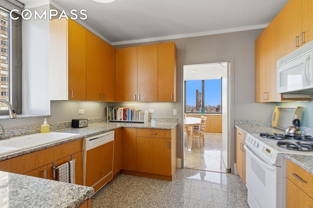 kitchen featuring white appliances, a sink, granite tiled floors, light stone countertops, and brown cabinets