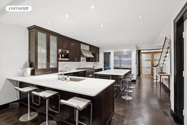 132 E 62nd St, New York City, NY 10065 - kitchen featuring wall chimney exhaust hood, a kitchen breakfast bar, a center island, a sink, and light countertops