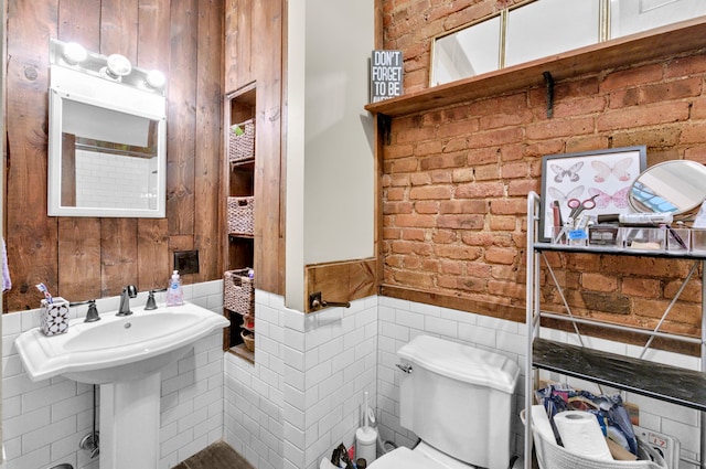 half bathroom featuring tile walls, a wainscoted wall, and toilet