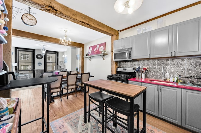 kitchen with gray cabinetry, stainless steel appliances, and an inviting chandelier