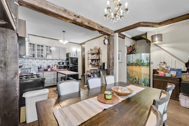 dining space featuring beam ceiling, an inviting chandelier, and light wood finished floors
