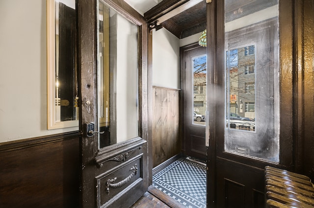 doorway to outside with wooden walls and a wainscoted wall