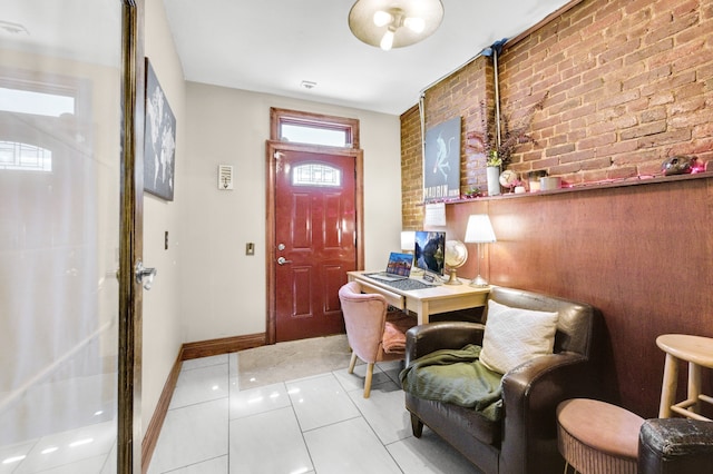 tiled foyer entrance featuring brick wall and baseboards