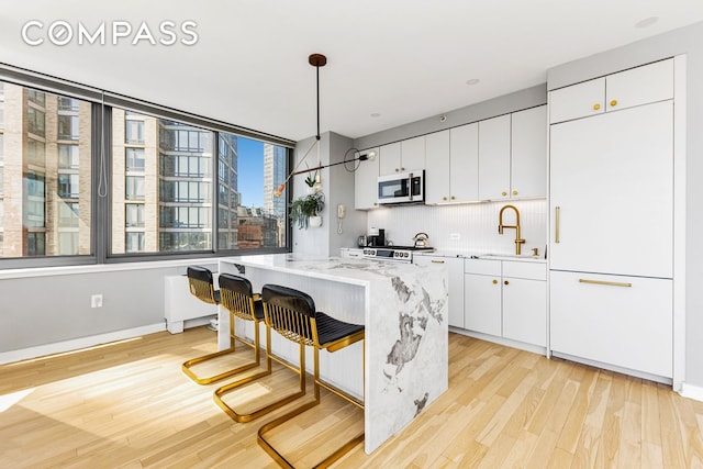 kitchen featuring a sink, light wood-type flooring, a kitchen island, and backsplash