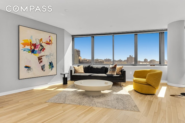 sitting room with wood finished floors, baseboards, plenty of natural light, and a view of city
