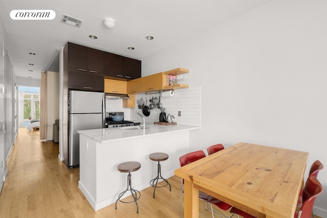 146 Clifton Pl Unit 2A, New York City, NY 11238 - kitchen featuring appliances with stainless steel finishes, a peninsula, light wood-style flooring, a kitchen bar, and recessed lighting