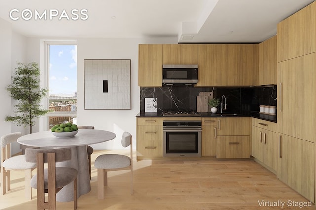 kitchen with stainless steel appliances, dark countertops, a sink, and tasteful backsplash