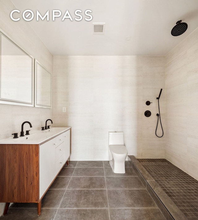 bathroom featuring visible vents, double vanity, toilet, a sink, and a tile shower