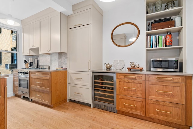 interior space with beverage cooler, appliances with stainless steel finishes, backsplash, and light wood-type flooring