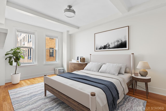 bedroom with baseboards, wood finished floors, and beamed ceiling
