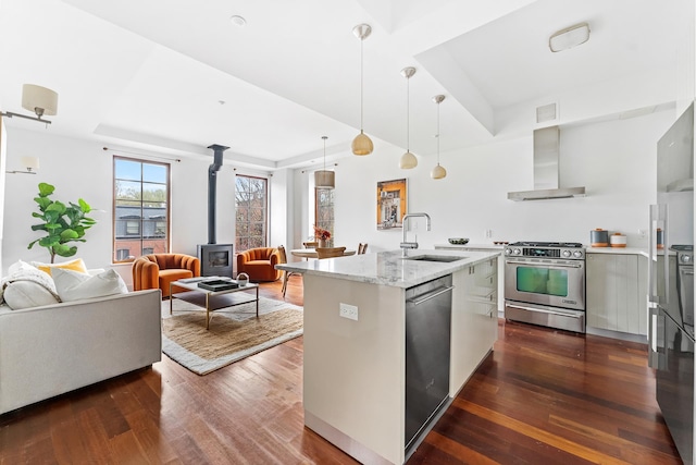 268 Cumberland St Unit 4A, New York City, NY 11205 - kitchen featuring appliances with stainless steel finishes, wall chimney exhaust hood, a sink, a wood stove, and dark wood-style floors