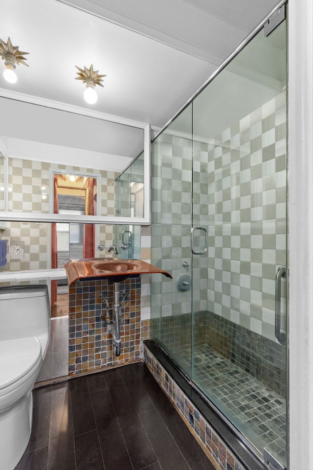 bathroom with tile walls, toilet, and a stall shower