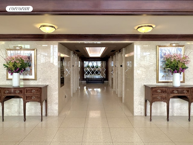 hall with ornamental molding and light tile patterned flooring