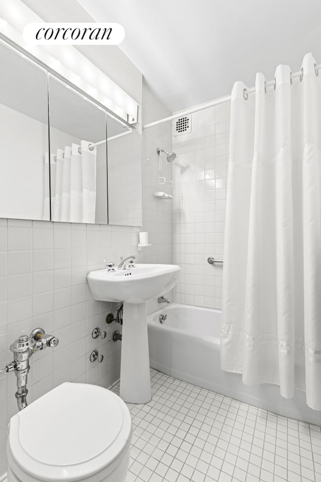 bathroom featuring shower / bath combination with curtain, tile patterned floors, toilet, and tile walls