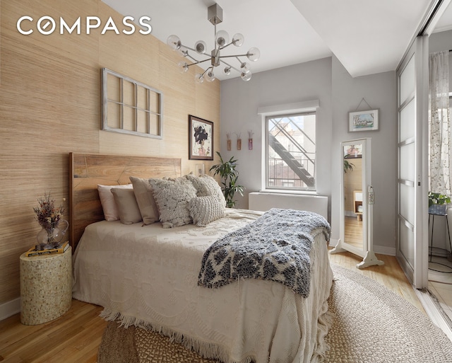 bedroom with light wood-type flooring, a chandelier, and baseboards