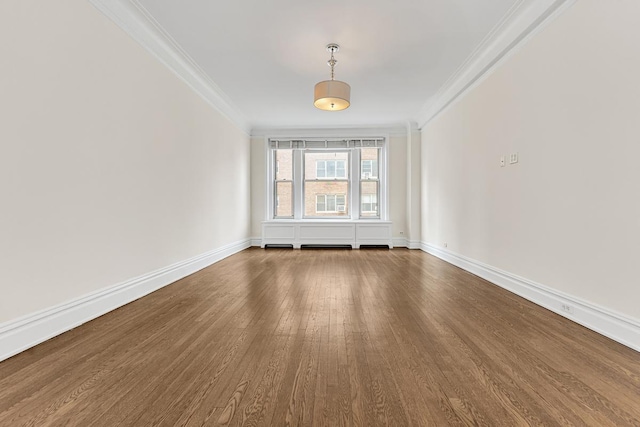 spare room with baseboards, ornamental molding, and dark wood-style floors