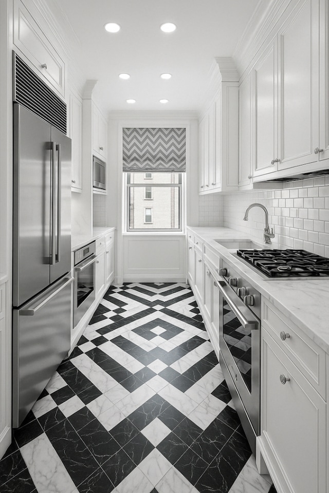 kitchen with a sink, ornamental molding, white cabinetry, and built in appliances