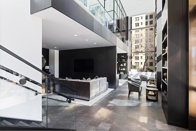 interior space with a healthy amount of sunlight, a towering ceiling, stairway, marble finish floor, and recessed lighting