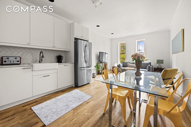 kitchen with freestanding refrigerator, crown molding, a sink, and light wood-type flooring