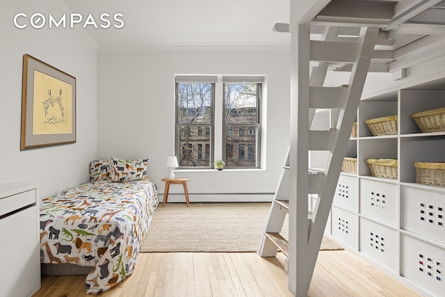 bedroom with a baseboard heating unit, ornamental molding, and wood finished floors