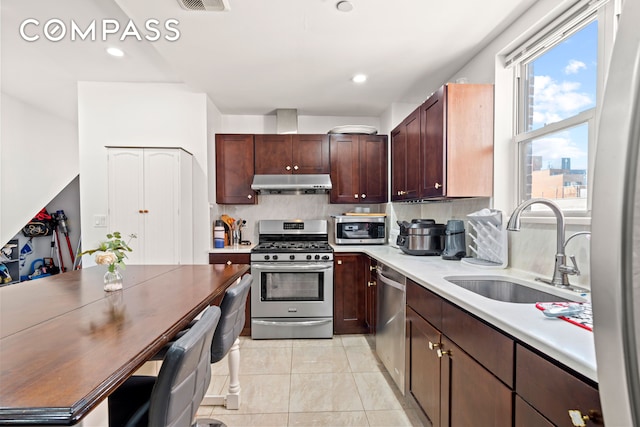 kitchen with a sink, light tile patterned floors, stainless steel appliances, light countertops, and under cabinet range hood