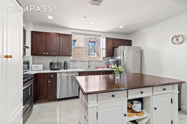 kitchen featuring stainless steel appliances, open shelves, visible vents, a sink, and tasteful backsplash