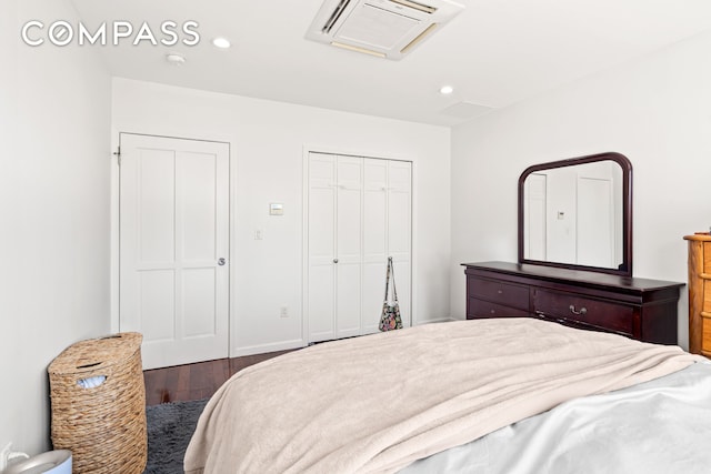 bedroom with a closet, wood finished floors, visible vents, and recessed lighting
