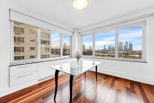 unfurnished dining area with a skyline view, wood finished floors, and baseboards