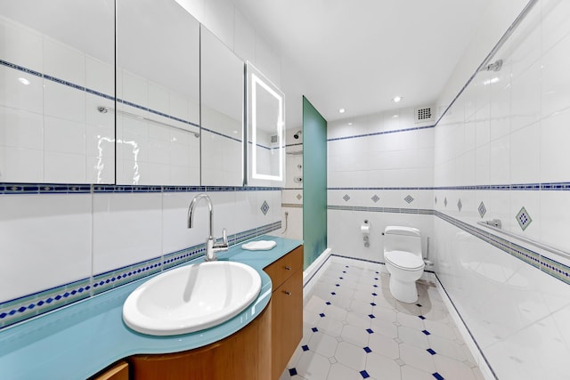 bathroom featuring tile walls, tiled shower, vanity, and toilet