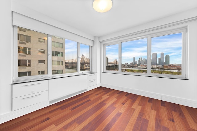 empty room featuring a view of skyline, dark wood-style flooring, and baseboards