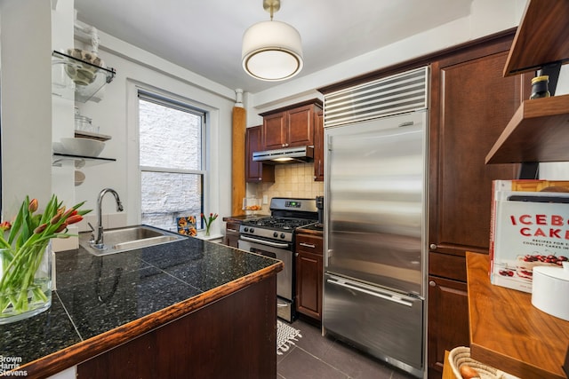 kitchen featuring stainless steel appliances, tile counters, a sink, under cabinet range hood, and decorative backsplash