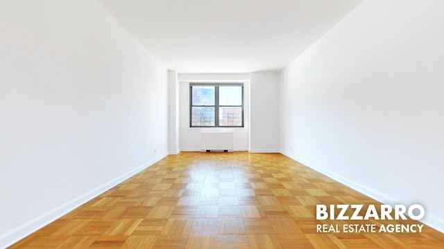 spare room featuring radiator and baseboards