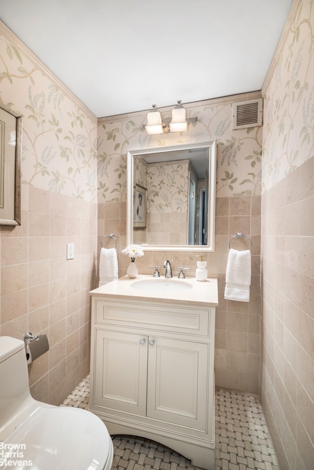 175 E 62nd St Unit 8B, New York City, NY 10065 - half bathroom with wallpapered walls, toilet, tile walls, vanity, and a wainscoted wall