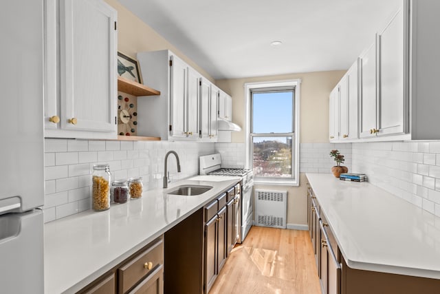 221 Mcdonald Ave Unit 6B, New York City, NY 11218 - kitchen featuring white gas range oven, radiator, fridge, a sink, and open shelves