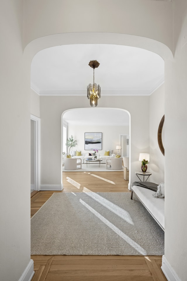foyer entrance with arched walkways, ornamental molding, a chandelier, and baseboards