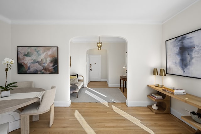 dining room with arched walkways, ornamental molding, hardwood / wood-style floors, and baseboards