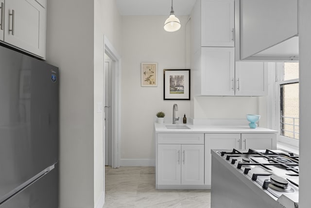 kitchen featuring a sink, marble finish floor, pendant lighting, light countertops, and freestanding refrigerator