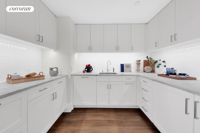 kitchen featuring decorative backsplash, white cabinets, dark wood-style floors, and a sink