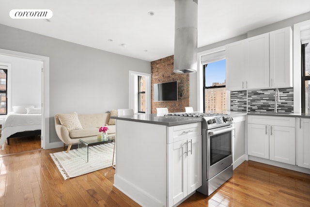 kitchen featuring stainless steel gas range, a peninsula, a sink, and open floor plan