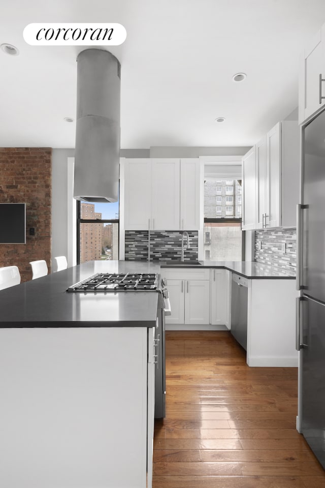 kitchen featuring appliances with stainless steel finishes, a sink, dark countertops, white cabinets, and backsplash