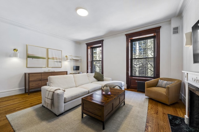 120 E 85th St Unit 2-E, New York City, NY 10028 - living room featuring radiator, wood finished floors, crown molding, a high end fireplace, and baseboards