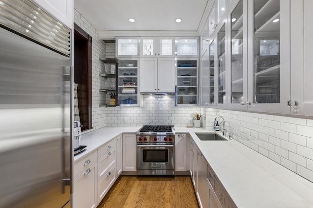 120 E 85th St Unit 2-E, New York City, NY 10028 - kitchen with high end appliances, a sink, light countertops, decorative backsplash, and white cabinets