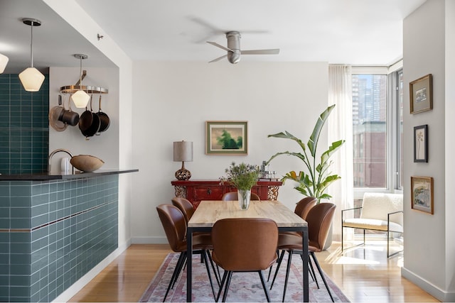 dining area featuring wood finished floors, ceiling fan, and baseboards