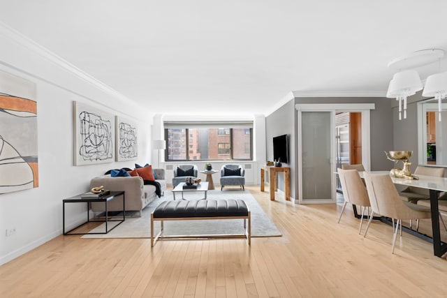 living area featuring light wood-style flooring, ornamental molding, and baseboards