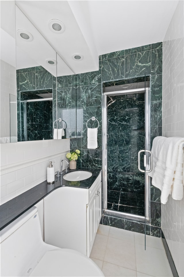 full bathroom with tile walls, a marble finish shower, tile patterned floors, and vanity