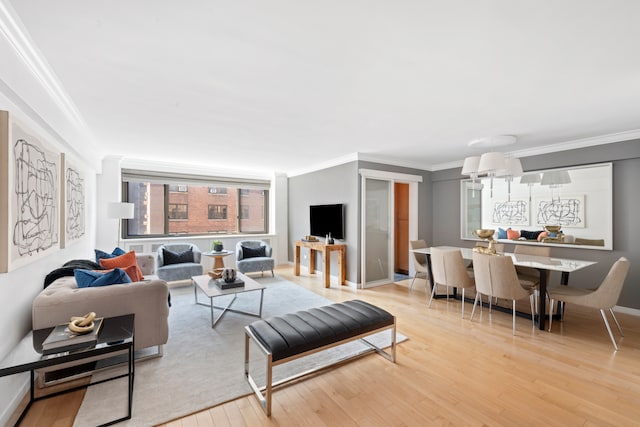 living area with ornamental molding, light wood-style floors, and baseboards