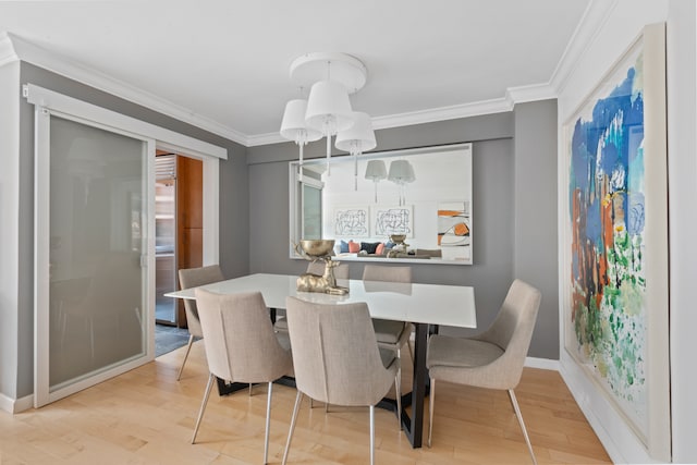 dining area featuring light wood-type flooring, crown molding, and baseboards