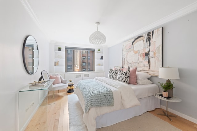 bedroom featuring ornamental molding, wood finished floors, and baseboards