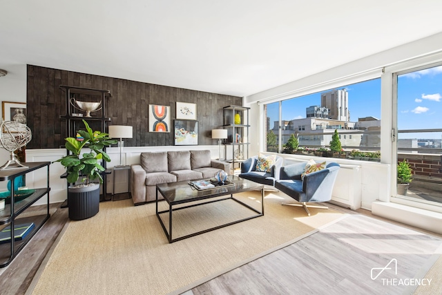 living room with wood finished floors, a city view, and wooden walls